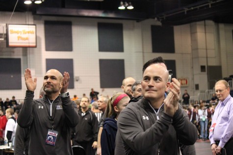 Head coach James Richardson and assistant coach Tom Foley follow the team during the team as they march through the Kellogg Arena. Richardson, Foley and the rest of the wrestling team coach staff led the team to a final season record of 26-4 and 8-0 in the O-K Red conference.