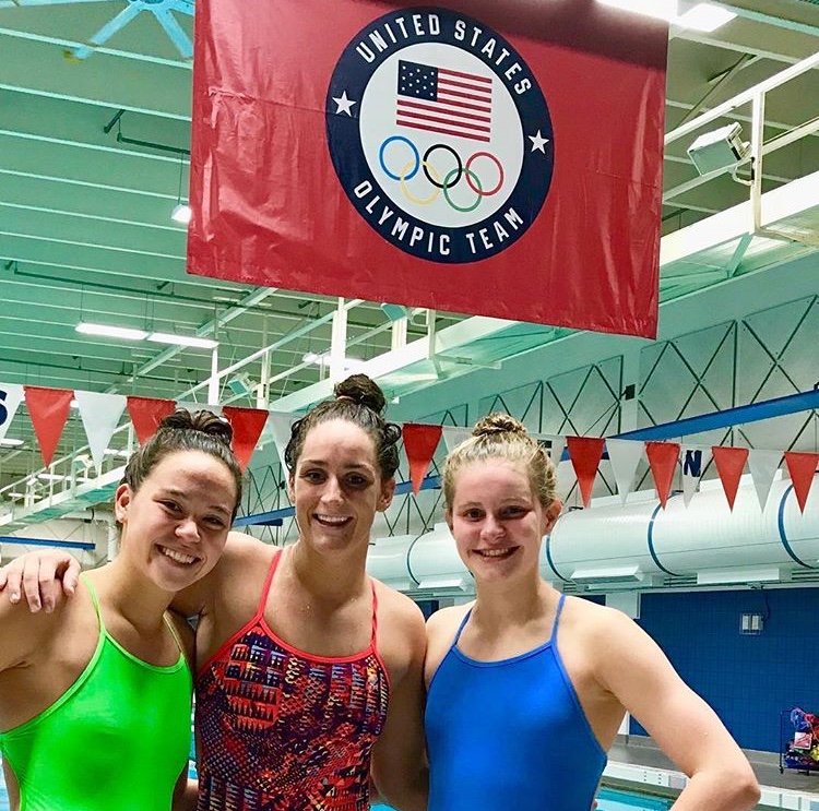 Sophomore Kathryn Ackerman poses for a picture in front of the Olympic USA swim team flag with some friends after a another day of training at the complex.