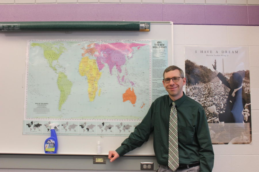 Jason Klinger poses under his world map with a smile