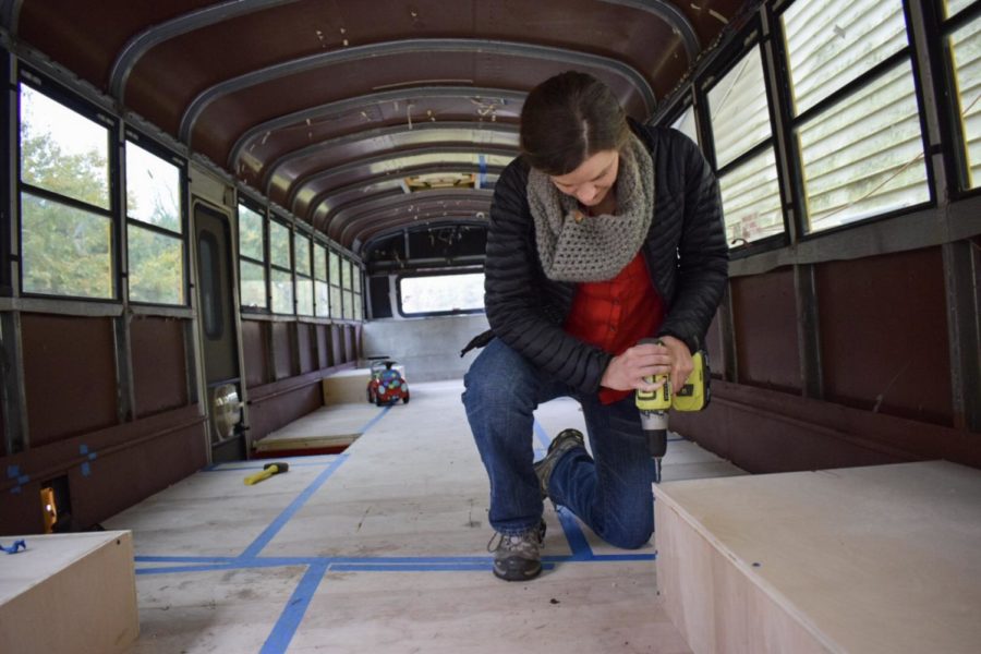 Laura Knochenhauer works on the interior of her familys bus. Right now it appears to be nothing more than plywood and tape, but soon it will be a fully functioning family home.