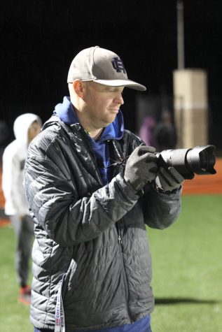 CAPTURING CLIPS: Teacher Josh Walters peers at the camera display as he films the football game. He puts together highlight videos for Grand Haven athletics. One of the coolest things for me to do is connect with the kids, Walters said. I dont have all the kids in class, so seeing them out there playing their sport or participating in whatever they like to do is a lot of fun. 