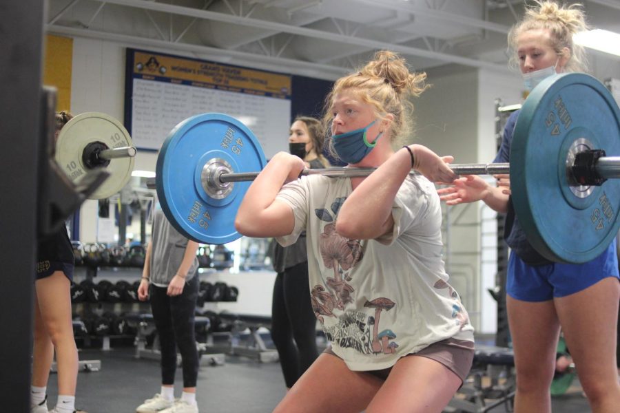 Chloe+Brackenbury%2C+assited+by+partner+Audrey+Cook%2C+works+on+her+squat+in+advanced+weightlifting+class+%28photo+credit+Megan+Voorhees%29.+