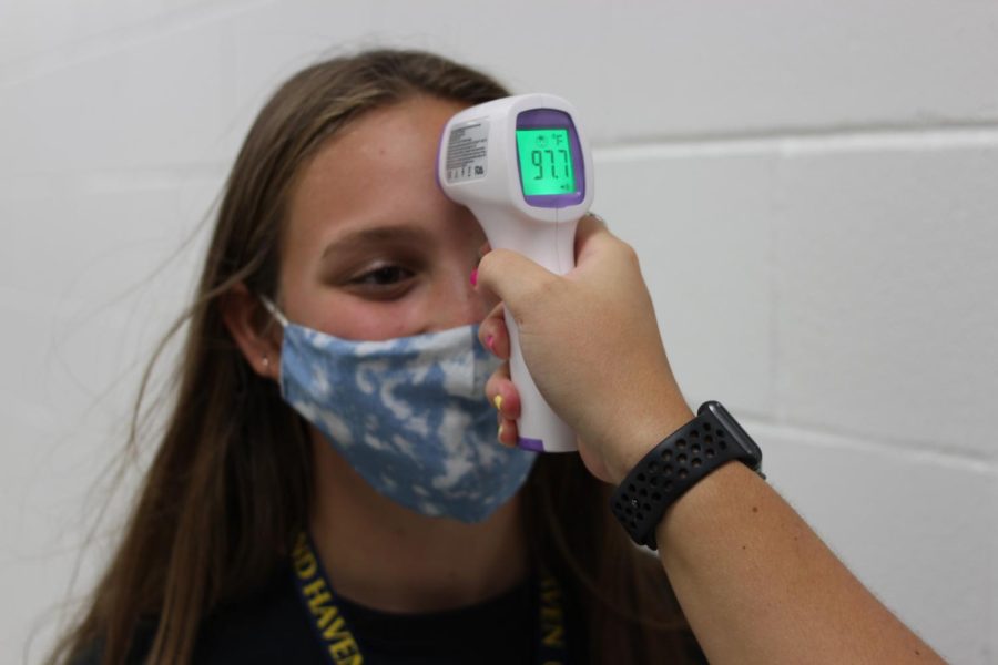 A student gets her temperature checked amidst the rise and fall of COVID-19 cases. 