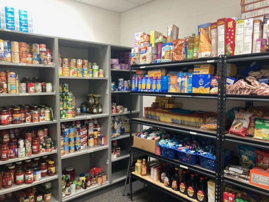 FULLY STOCKED: The food pantry is filled to the brim after the Give and Glow food drive in February. Student volunteers Ava Prieditis and Graci Chittenden work to keep it that way. 