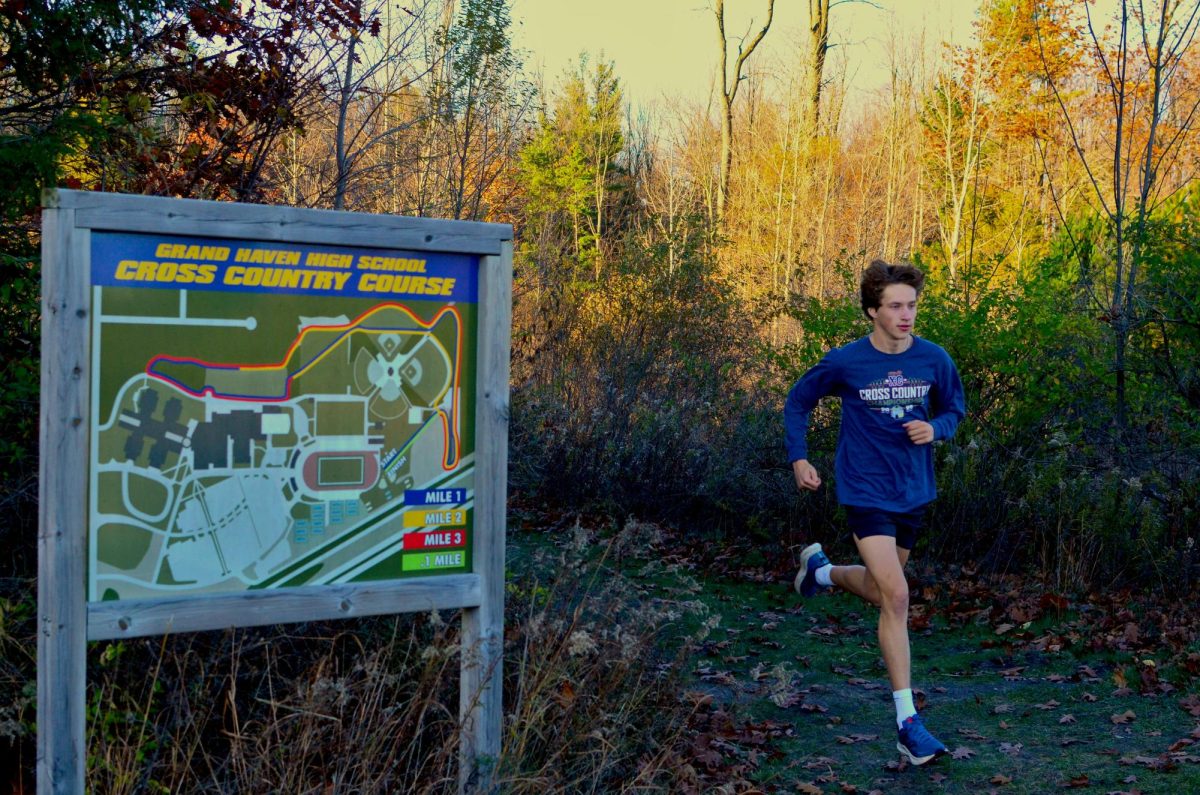 Team captain Roman Smith runs past the map of the GHHS cross country course where he ran his first race. I just stuck with it and I grew to love it and its a big part of my life now, Smith said.