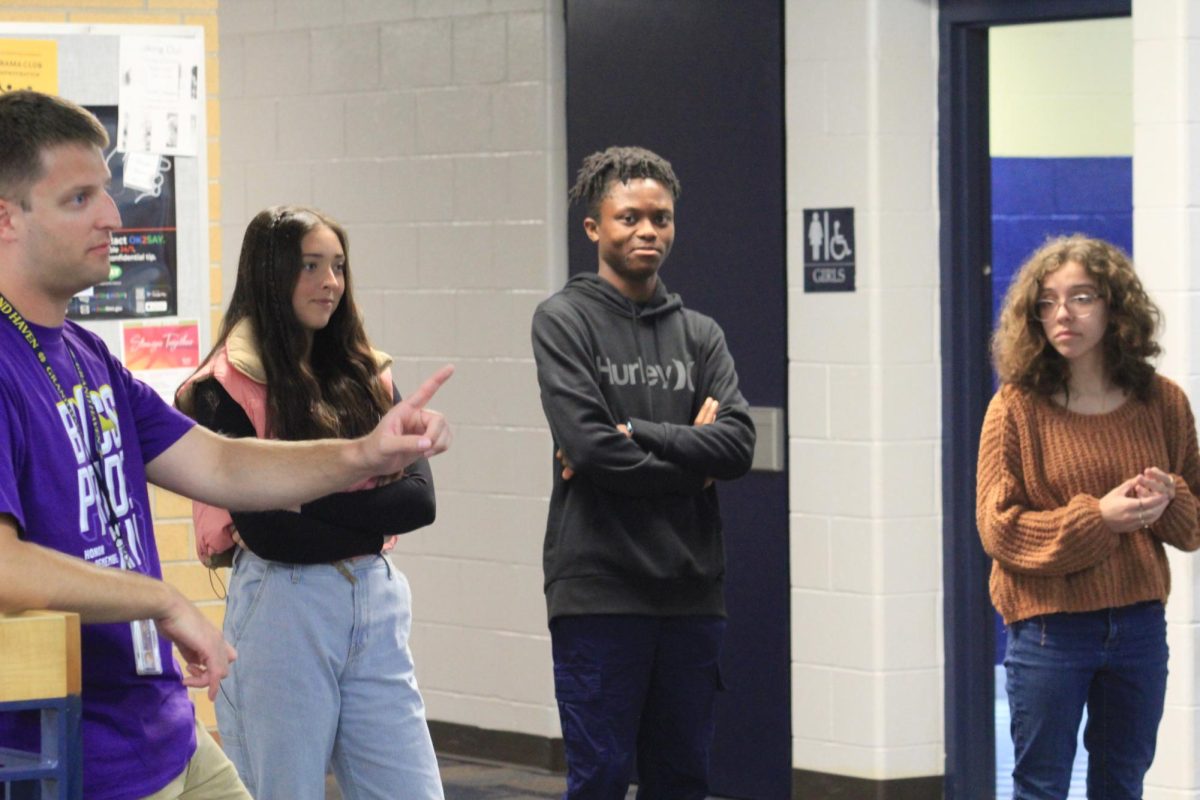 Daniel Newton discusses the Rutherford gold foil experiment with his 3rd hour honors Chemistry class.  Pictured left to right are junior Reese Morgan. senior Ben Eisnor, and junior Ana Walker. 