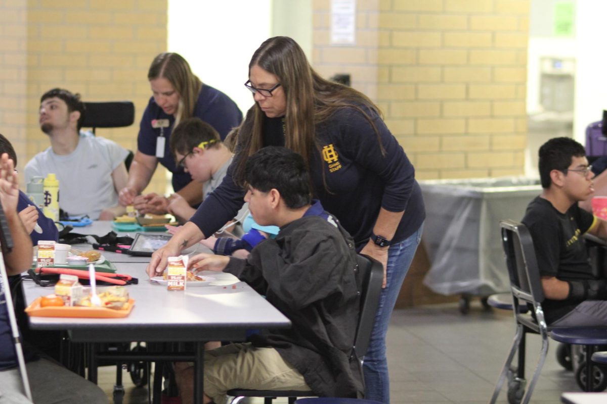 Special education assistant Daneen Tripp helps Elias Rodriguez in the cafeteria get settled for lunch.  " I put a lot of love and patience into all of the kids, " said Tripp. 