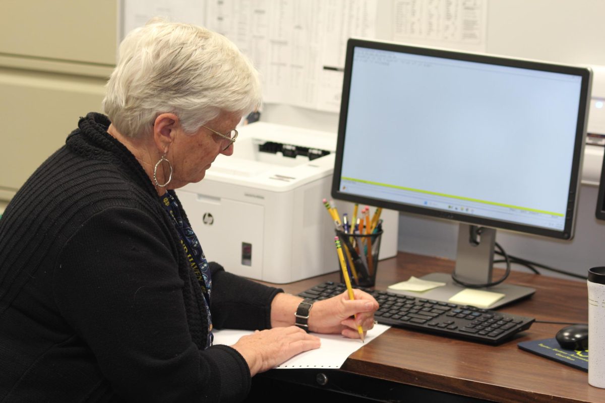 Braillist Becky Karsies finalizes a document after using a braille printer to emboss paper with braille dots. The document helps communicate with visually impaired students and help them learn information in their classes.