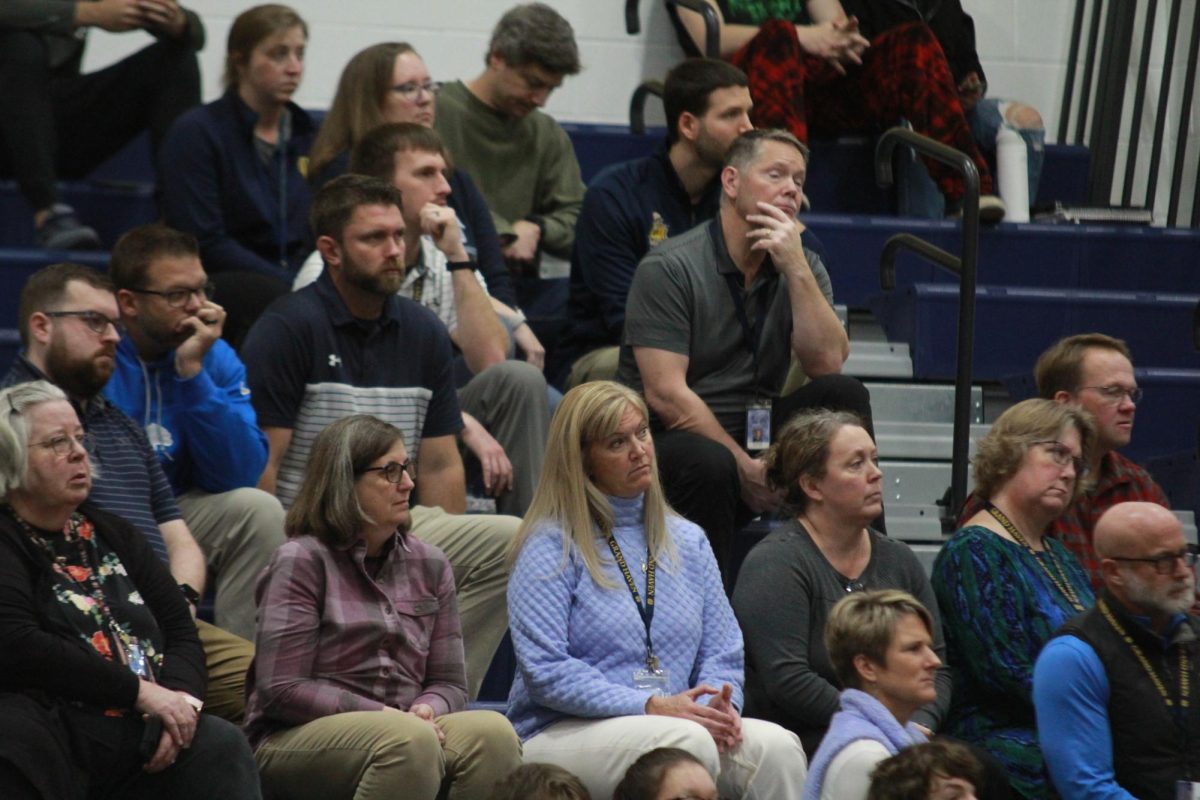 A group of teachers gathered in the fieldhouse for the Veterans' Day assembly. The new superintendent, Kristin Perkowski, was present to give a speech.